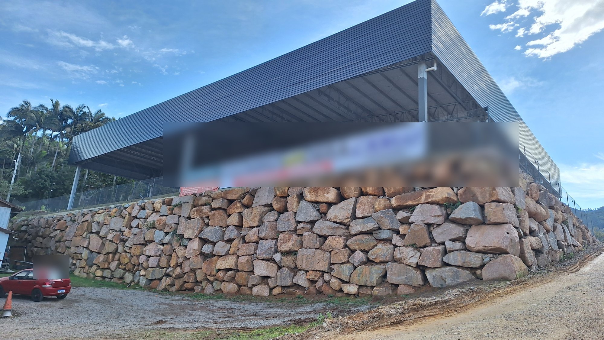 Muro de enrocamento arrumado sustentando o platô de um galpão industrial